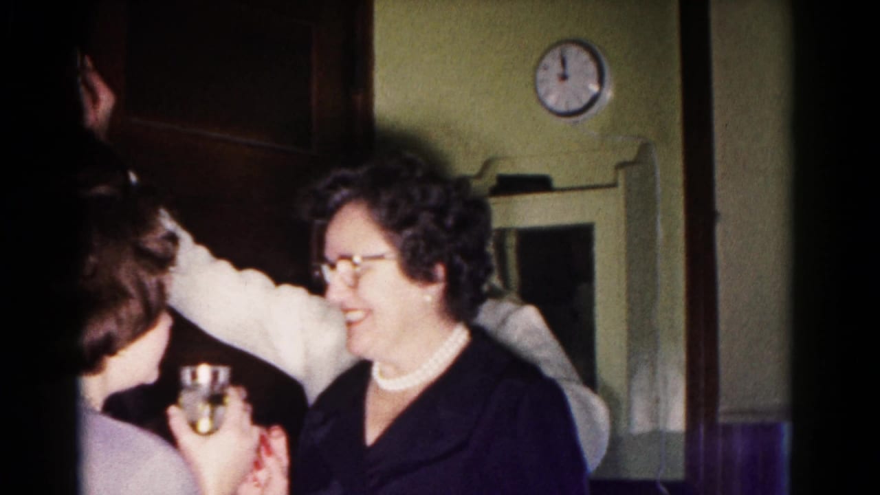 Woman smiles beside another guest holding a drink in a crowded room.