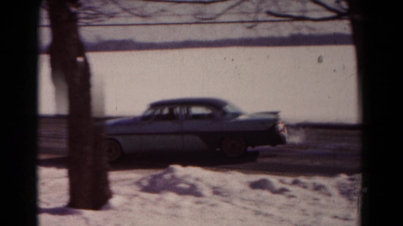 The car continues along the snowy Hagerstown street, partly obscured by trees and window framing in the 8mm shot.