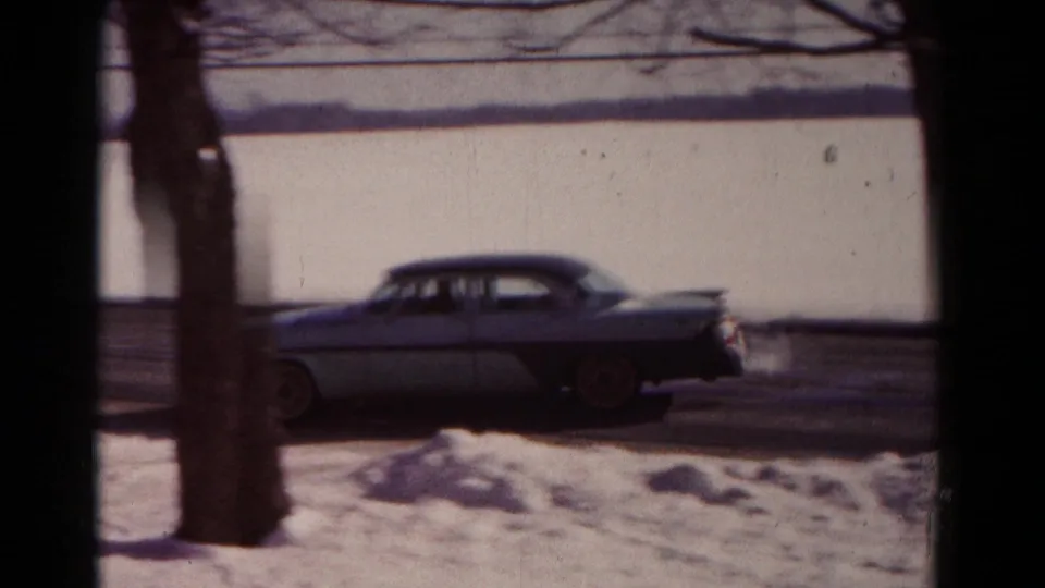 The car continues along the snowy Hagerstown street, partly obscured by trees and window framing in the 8mm shot.