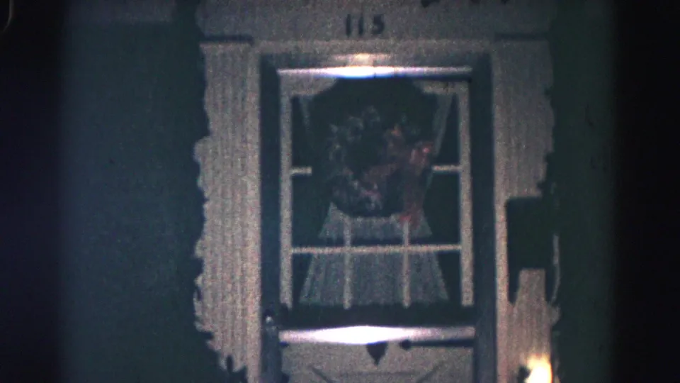 1958 Hagerstown night shot of house number 115 above a front door with a wreath, curtains, textured trim, and small exterior light.