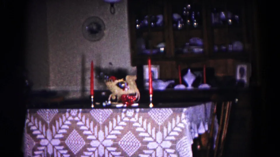 Candlelit dining setup in a Hagerstown, Maryland private home, with red tapers, centerpiece, patterned cloth, and glassware behind.