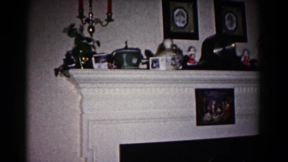 1958 Hagerstown interior showing a white mantel arranged with framed photos, figurines, red candles, and household keepsakes.