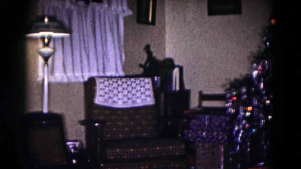 1958 Hagerstown Christmas interior with a patterned chair, floor lamp, curtained window, and illuminated tree.