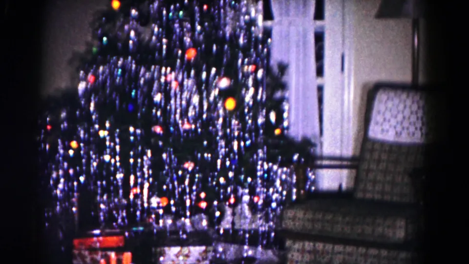 1958 Hagerstown frame showing the decorated tree near white curtains, with wrapped presents below and a patterned armchair at the side.