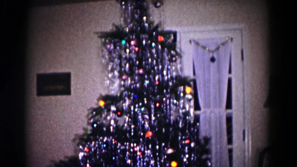 1958 Hagerstown frame showing a decorated Christmas tree near white curtains, a small wall picture, and part of a patterned chair.
