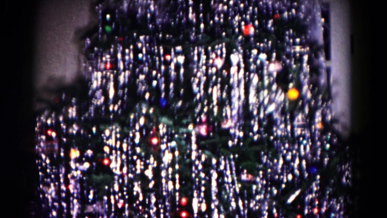 Close 1958 8mm view of a tinsel-covered Christmas tree with colored lights in a Hagerstown interior.