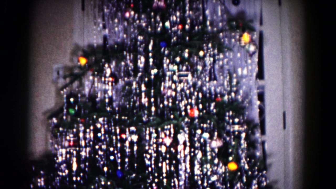 Decorated Christmas tree with tinsel, ornaments, and colored lights indoors.