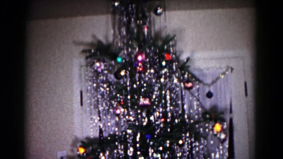 Final frame of the indoor Christmas tree in 1958 Hagerstown footage, with shimmering tinsel, colored ornaments, lights, and a doorway nearby.