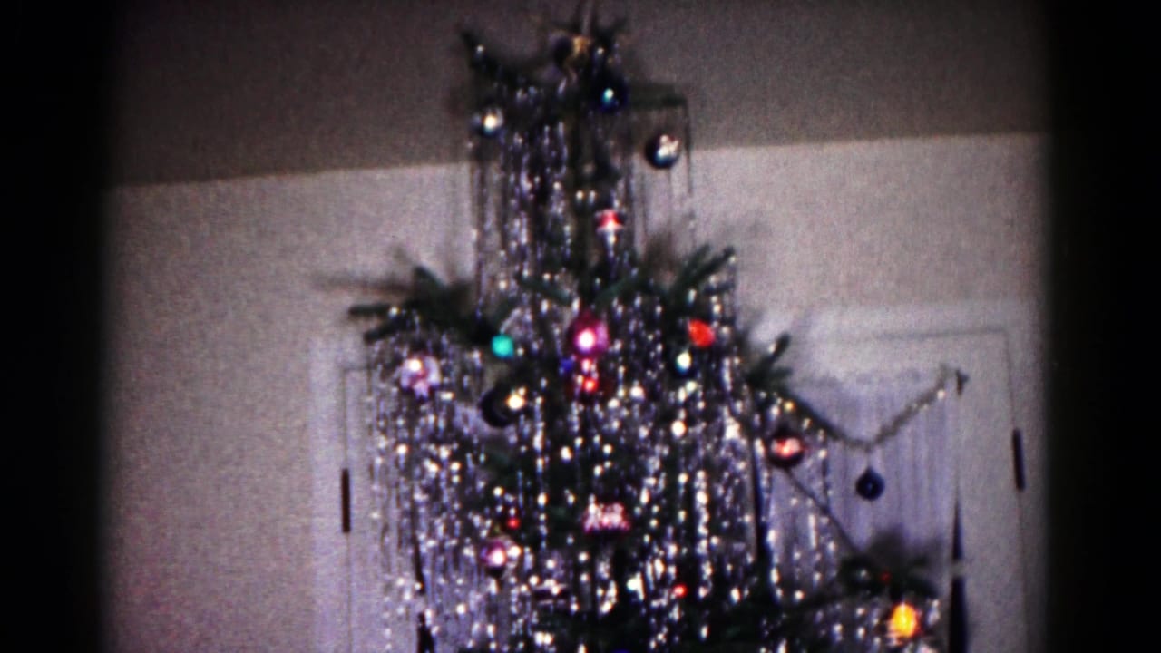 A 1958 Hagerstown home-movie frame shows an aluminum Christmas tree with reflective tinsel and ornaments near an interior doorway.