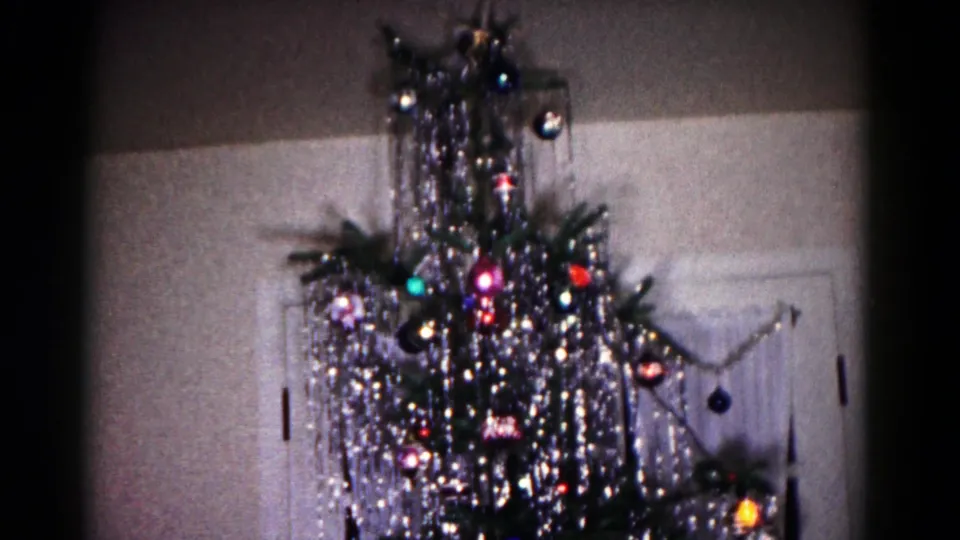 A 1958 Hagerstown home-movie frame shows an aluminum Christmas tree with reflective tinsel and ornaments near an interior doorway.