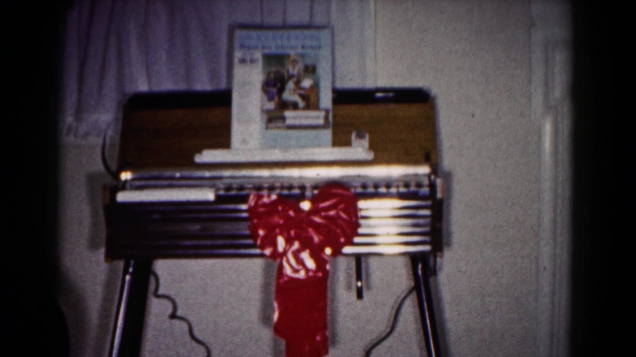 The home organ remains centered with a shiny red bow, keyboard, printed music book, curtains, and paneled interior wall.