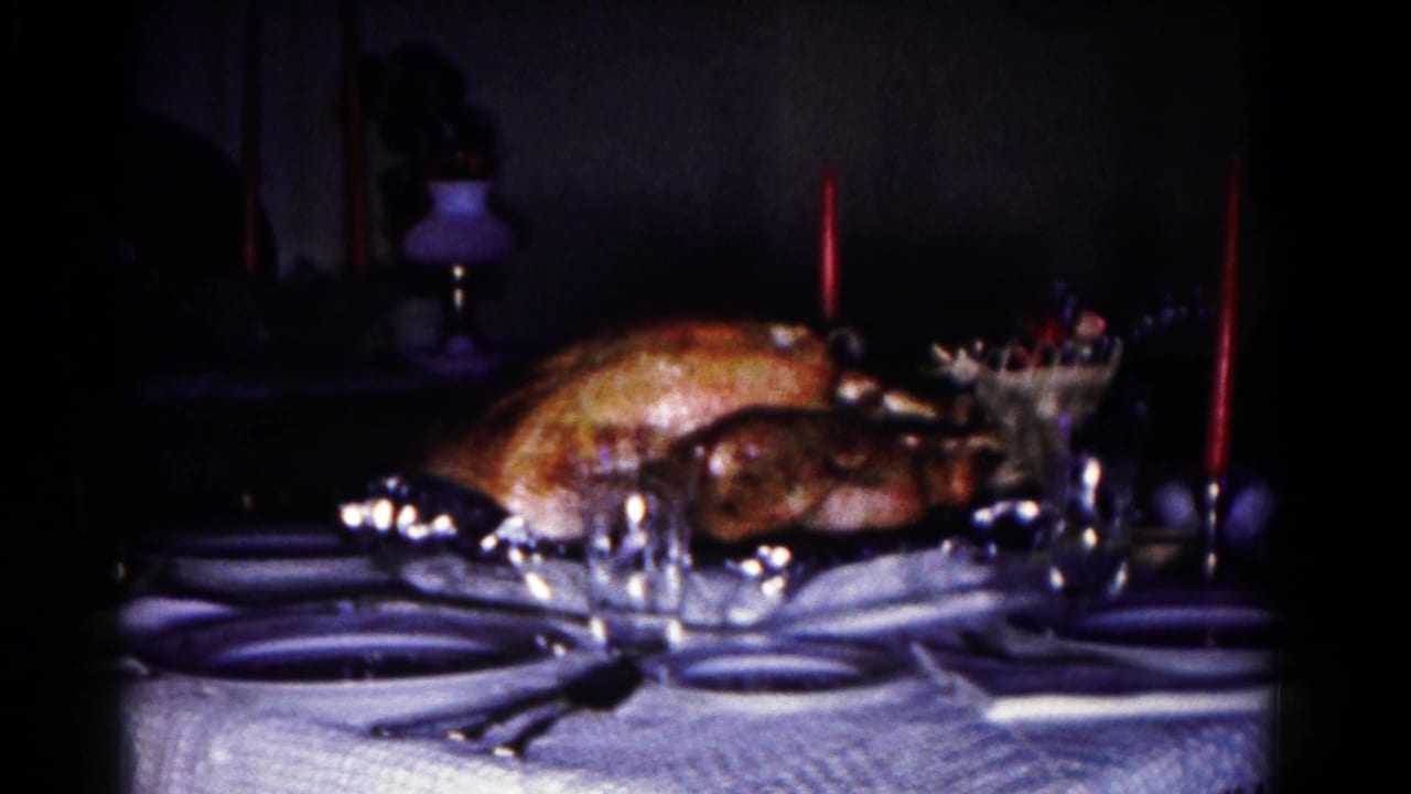 1958 Hagerstown home-movie frame of a roasted turkey on a formal dining table with glassware and tall red candles.