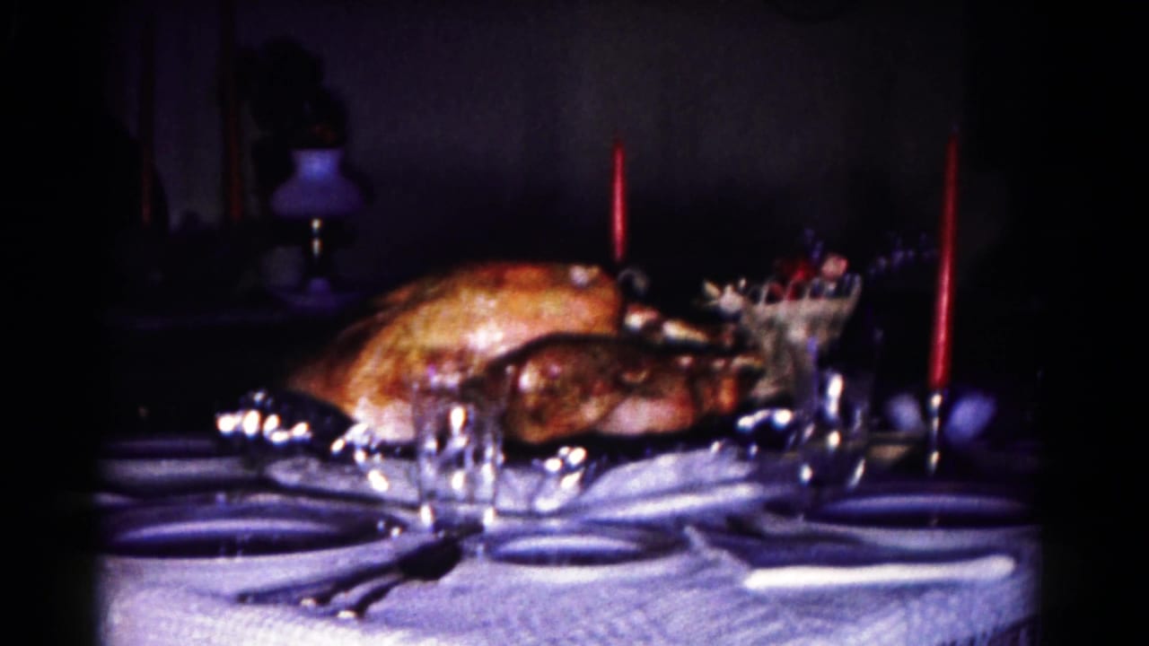 1958 Hagerstown dining table view with roasted turkey, place settings, clear glasses, and red candles in low light.