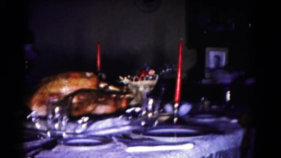 1958 Hagerstown home-movie frame showing a turkey dinner table with candles, glassware, and background decor.