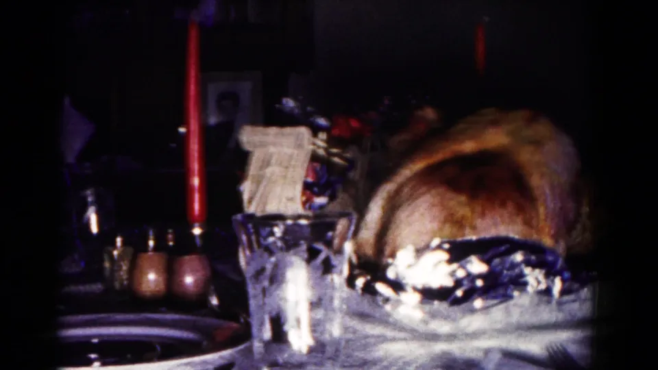 1958 Hagerstown interior frame with a roasted turkey centerpiece, red candles, glassware, and dim household furnishings.