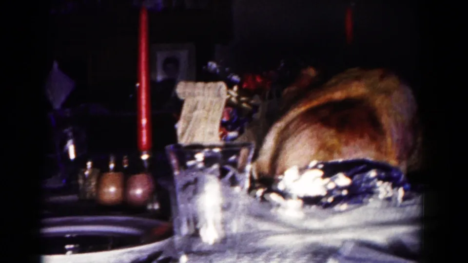 Final 1958 Maryland home-movie frame of the roasted turkey centerpiece on a set dining table in a dark private room.