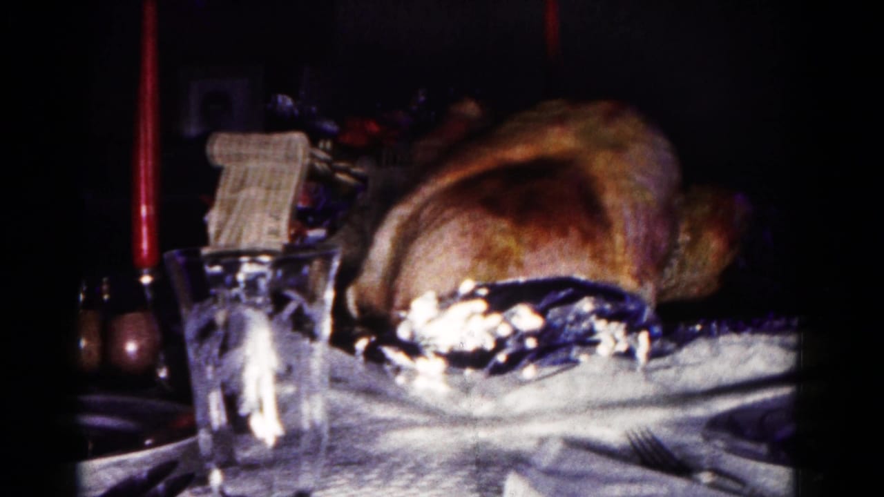 Roasted turkey on a holiday table with a red candle and glassware nearby.