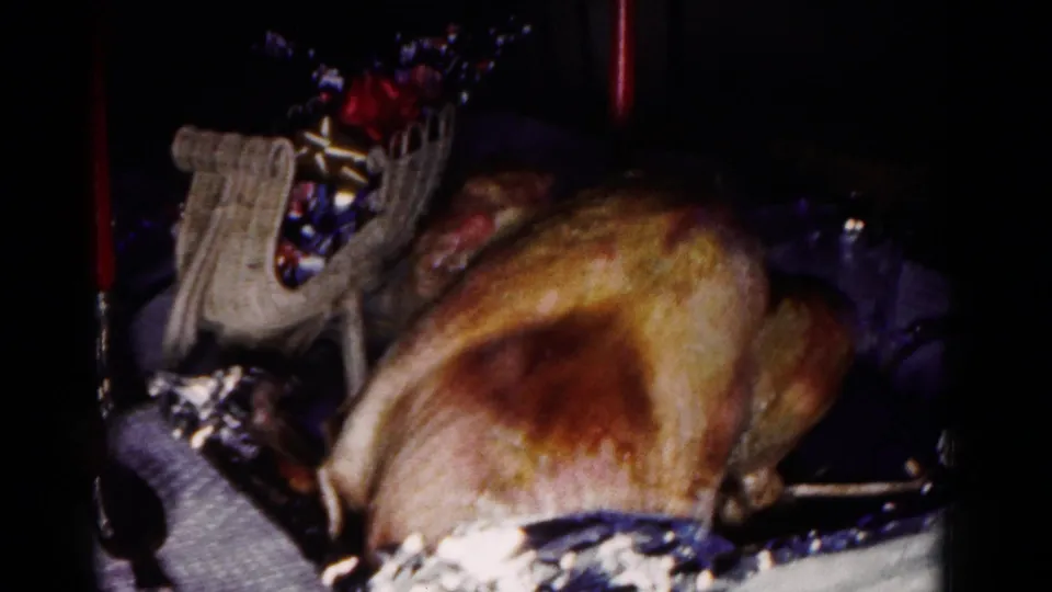 1958 Hagerstown home-movie view looking down at a roasted turkey, decorative basket, red candle, and table linens.