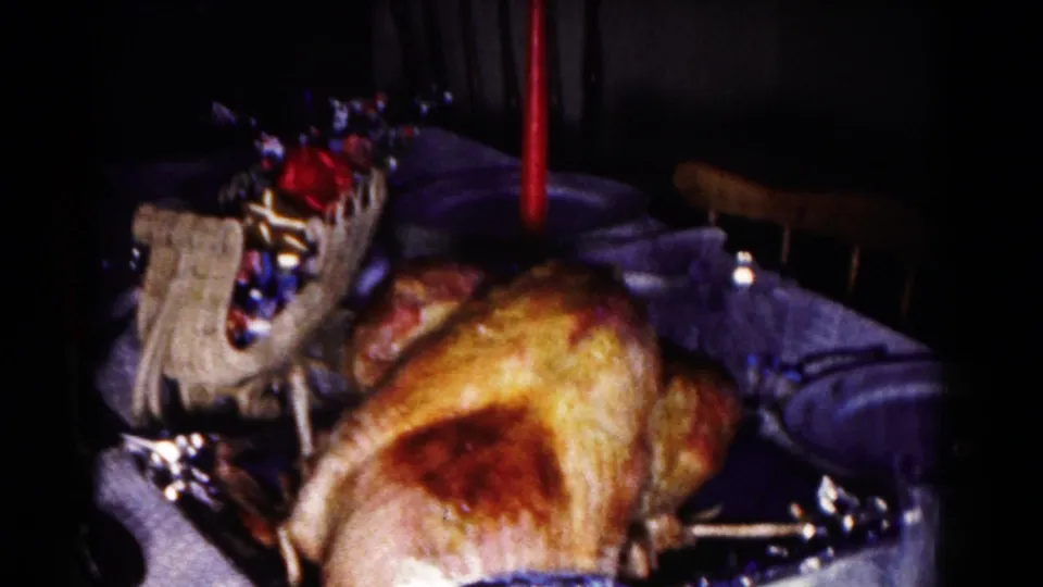 1958 Hagerstown frame showing the turkey from a shifted angle, with a red candle, decorative basket, tablecloth, and chair in the dim room.