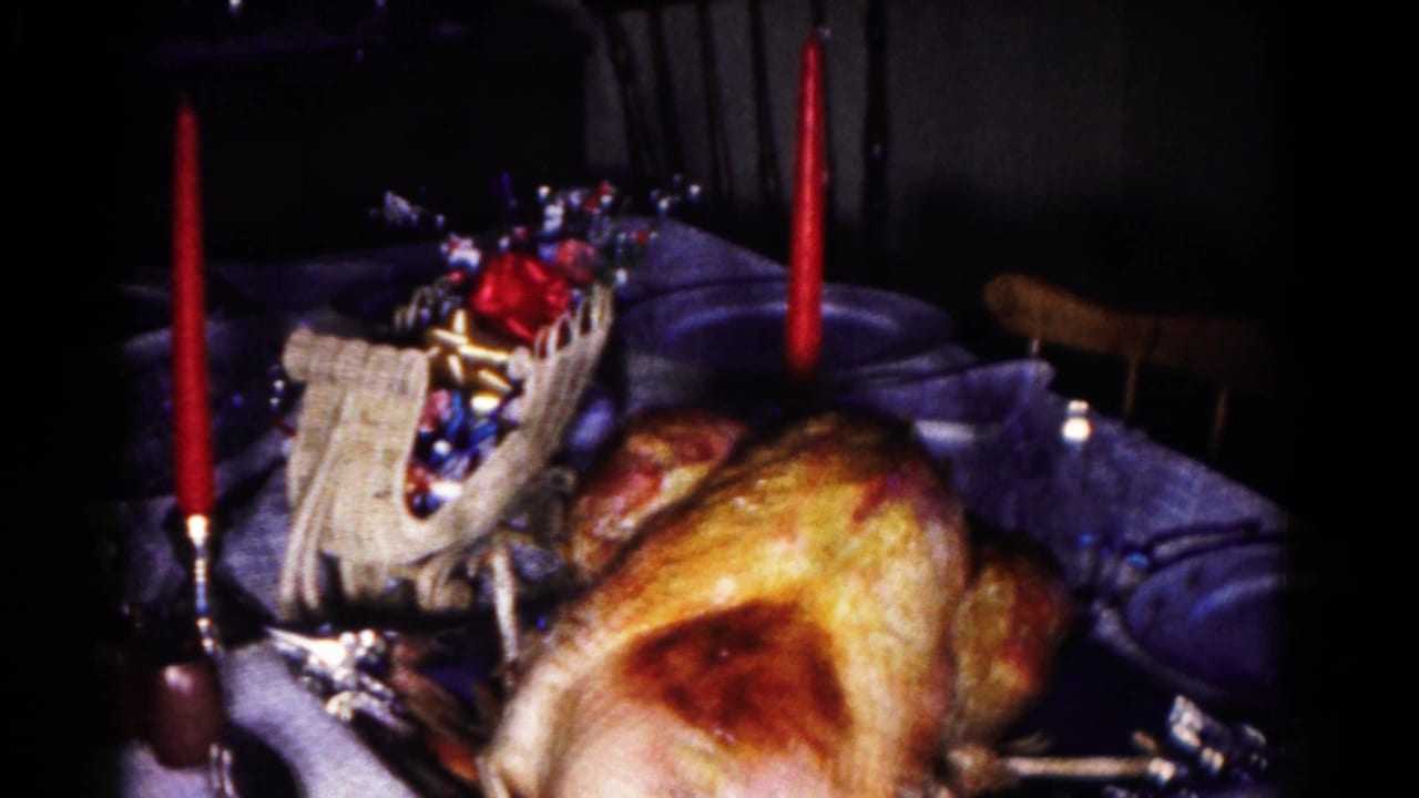 1958 Hagerstown home-movie frame showing a holiday table with roasted turkey, red candles, place settings, glassware, and a woven candy basket.