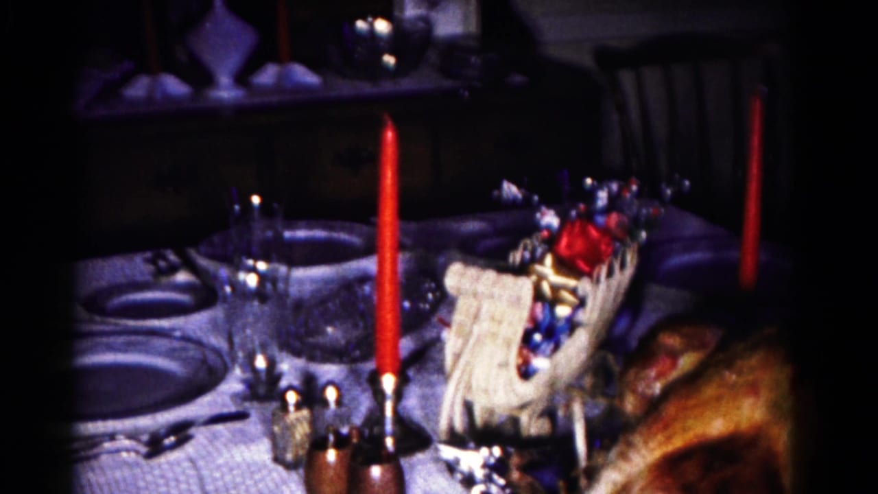 Holiday table detail with candy basket, red candle, plates, glassware, and part of a roasted turkey.