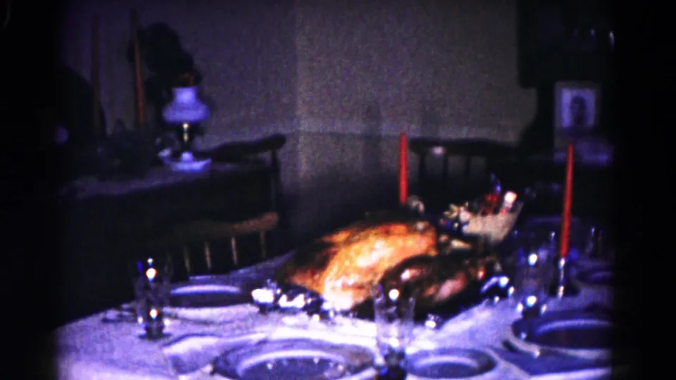 Final 1958 Hagerstown frame showing the holiday table from farther back, with turkey, red candles, dishes, glassware, chairs, and wall decor.