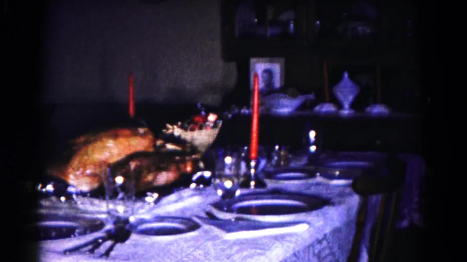 Late frame from the 1958 Hagerstown dining-room clip, showing the holiday table from a slightly shifted angle with turkey, candles, glassware, and chairs.