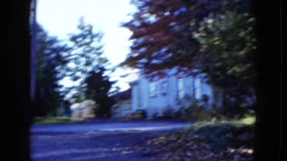1958 Las Vegas street-side view showing a pale residential house, roadside pavement, trees, and leaf-strewn ground.
