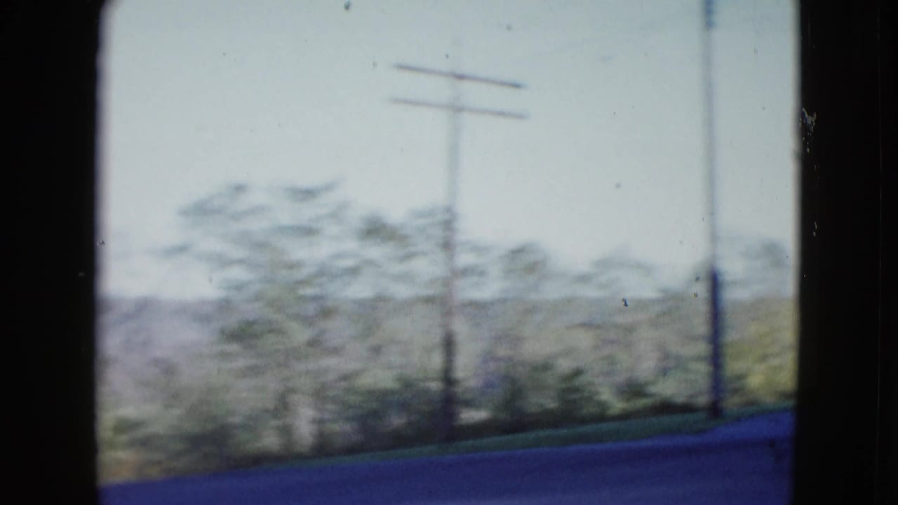 Blurred roadside utility poles beside desert shrubs and low hills.
