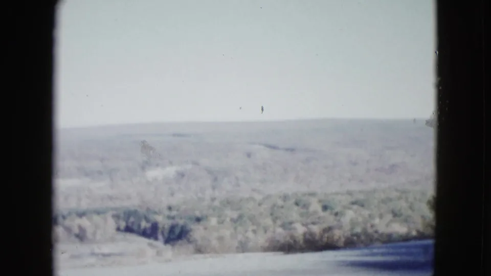 1958 Las Vegas-area 8mm view of open scrubland and low desert hills filmed from a moving vehicle on a bright day.