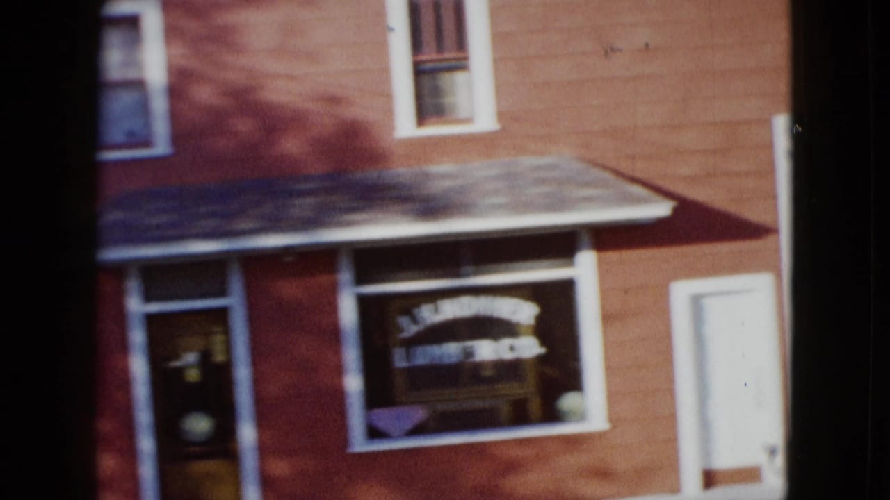 Porch-front red building with white-trimmed windows and visible window lettering.