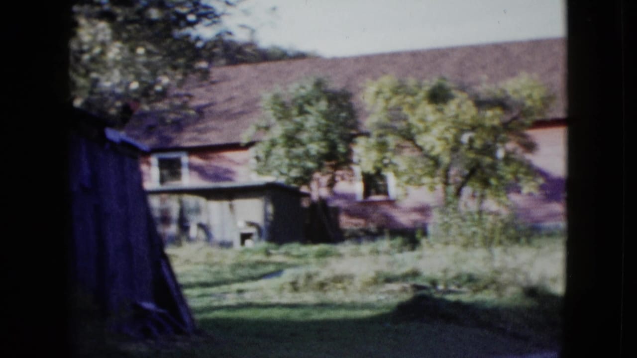 1958 8mm frame showing a weathered house, trees, grass, and shaded window or doorway edges in the reported Las Vegas area.