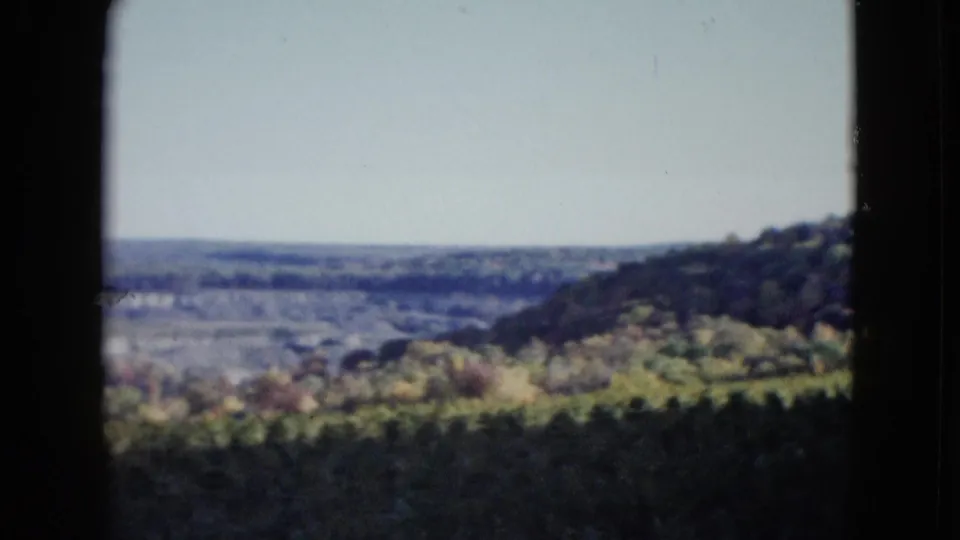 1958 8mm landscape frame showing a wooded slope and broad hazy valley, based on the supplied Las Vegas metadata.
