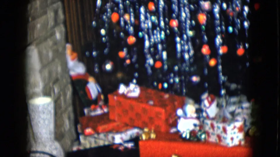1958 Las Vegas home interior with wrapped Christmas presents, Santa figure, stone wall edge, and a tinsel-covered tree.