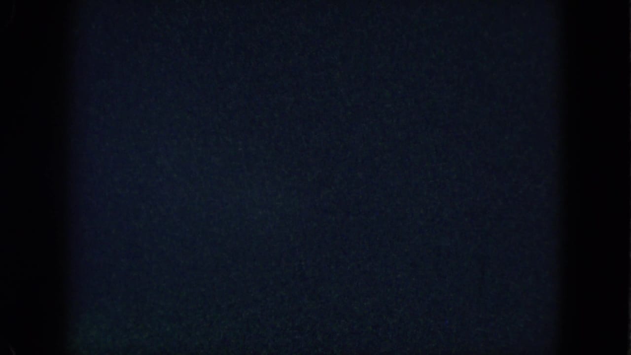 Mostly dark film frame with a narrow strip of interior detail along the bottom.