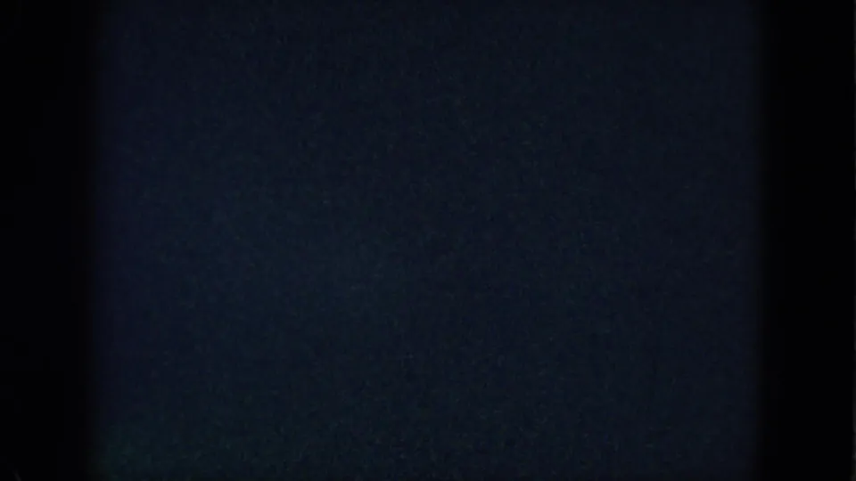 Dark 1958 8mm frame from Las Vegas with only a lower sliver of room detail visible beneath heavy shadow.