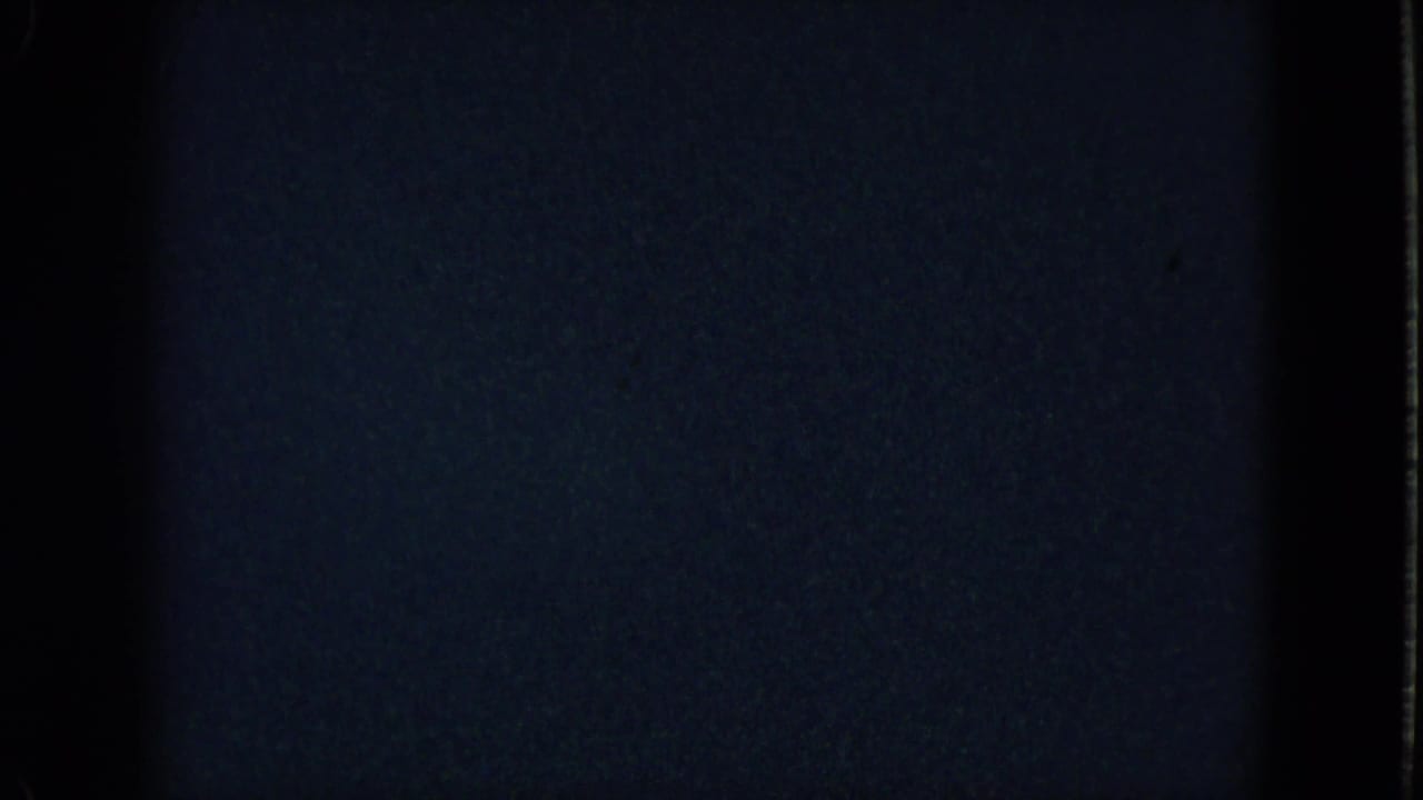 Underexposed Las Vegas home-movie frame with heavy darkness and a small band of visible interior detail near the bottom.