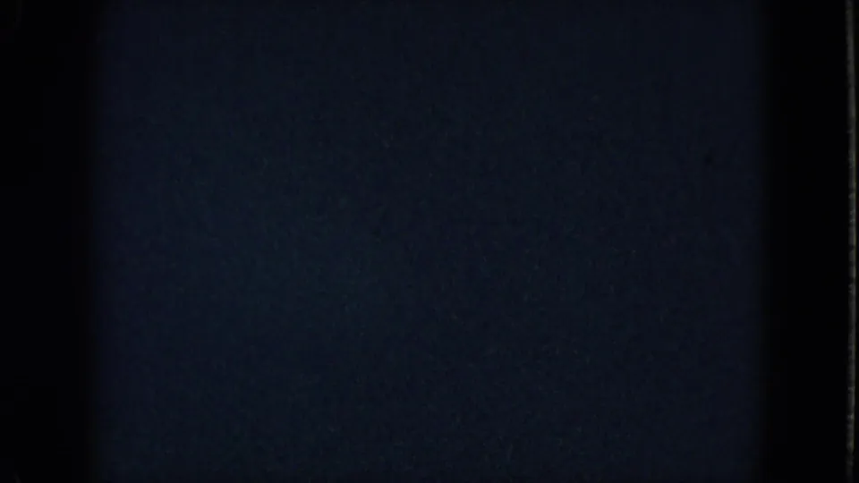 Underexposed Las Vegas home-movie frame with heavy darkness and a small band of visible interior detail near the bottom.