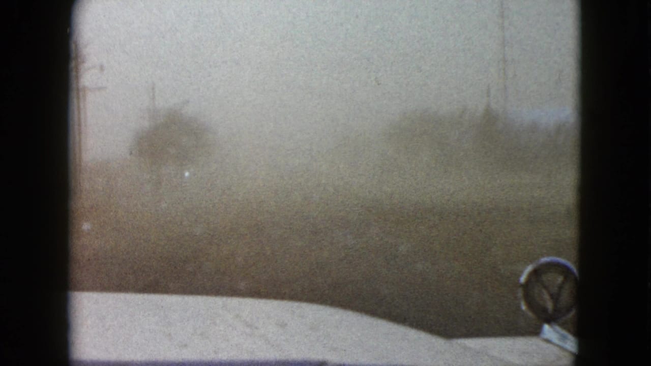 Windshield POV from a moving car in the Las Vegas area, with visibility reduced by dust or haze.