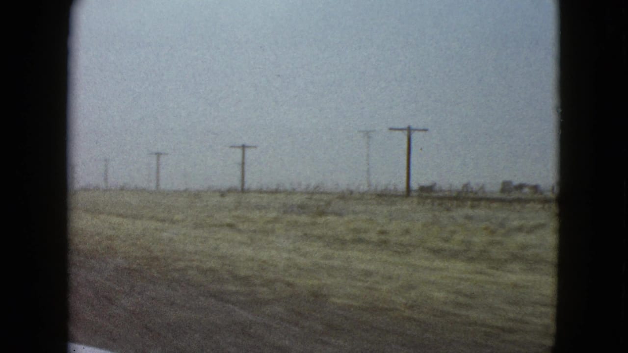 Flat roadside landscape with utility poles under a hazy sky.