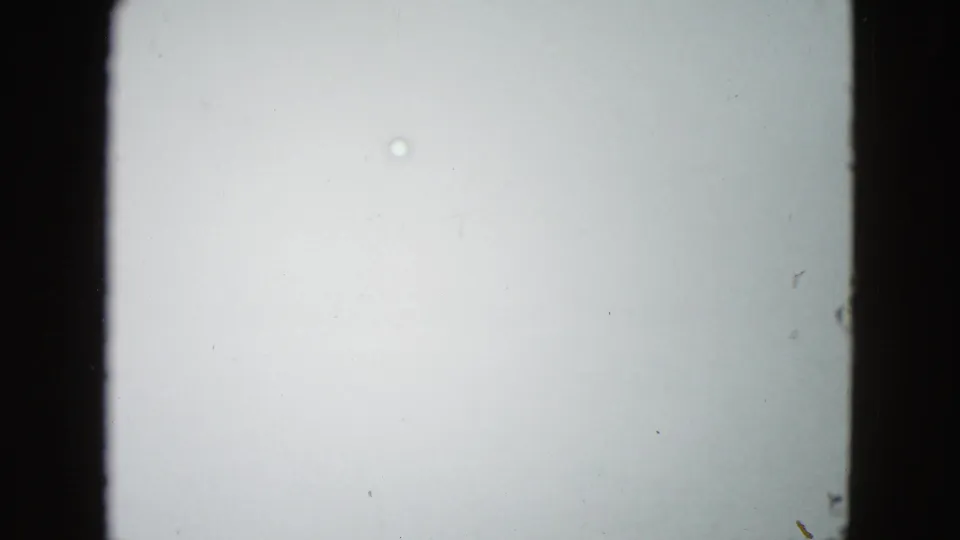 The road has nearly vanished in a pale fog-filled 1958 driving frame, with only film texture and faint specks visible.