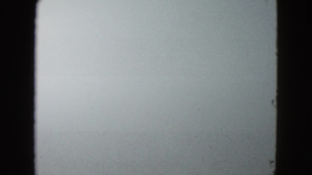 1958 8mm frame from Las Vegas showing dense white fog through a vehicle windshield with dark gate edges.