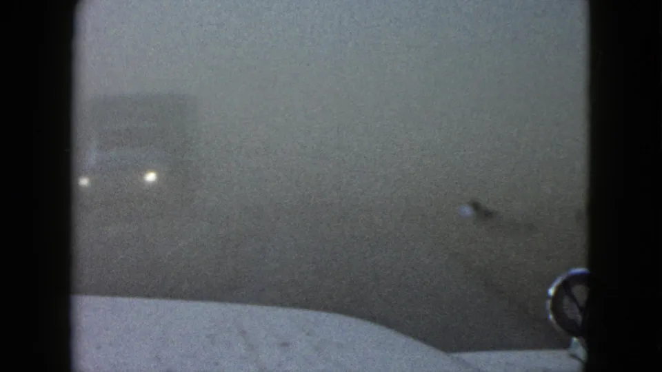 A foggy 1958 Las Vegas road view shows distant headlights and a blurred truck form beyond the vehicle hood.