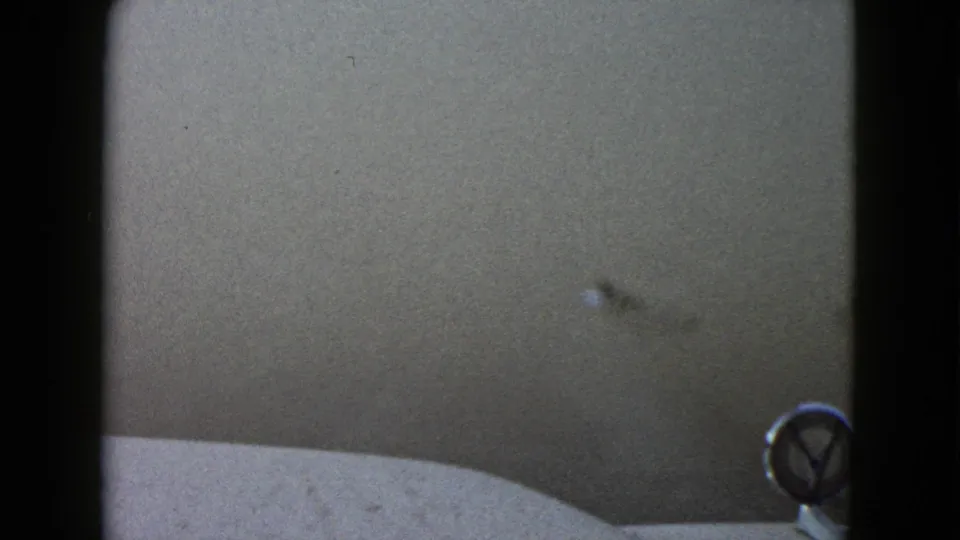 The later 1958 Las Vegas frame shows thinning fog, a faint truck shape, and the car hood with a round emblem in the foreground.