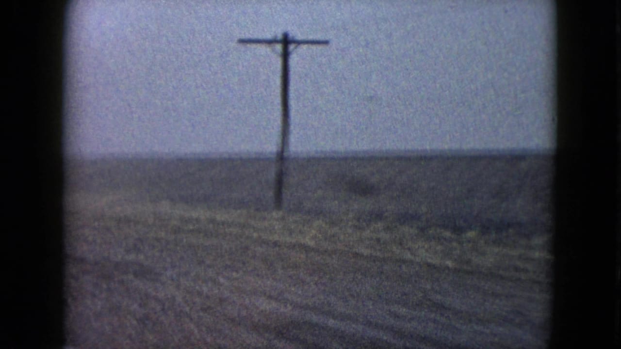 1958 Las Vegas-area road-trip frame with a utility pole and sparse open ground receding into a foggy or hazy horizon.