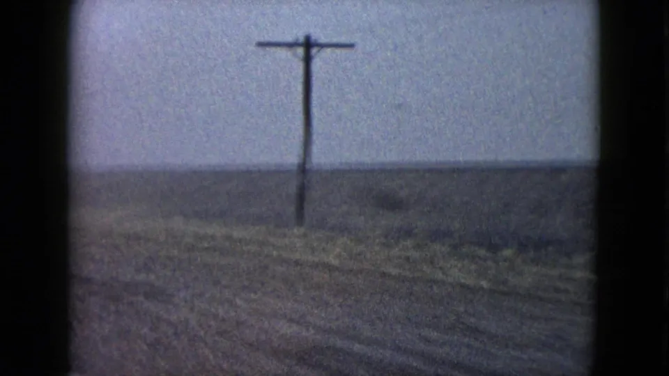 1958 Las Vegas-area road-trip frame with a utility pole and sparse open ground receding into a foggy or hazy horizon.