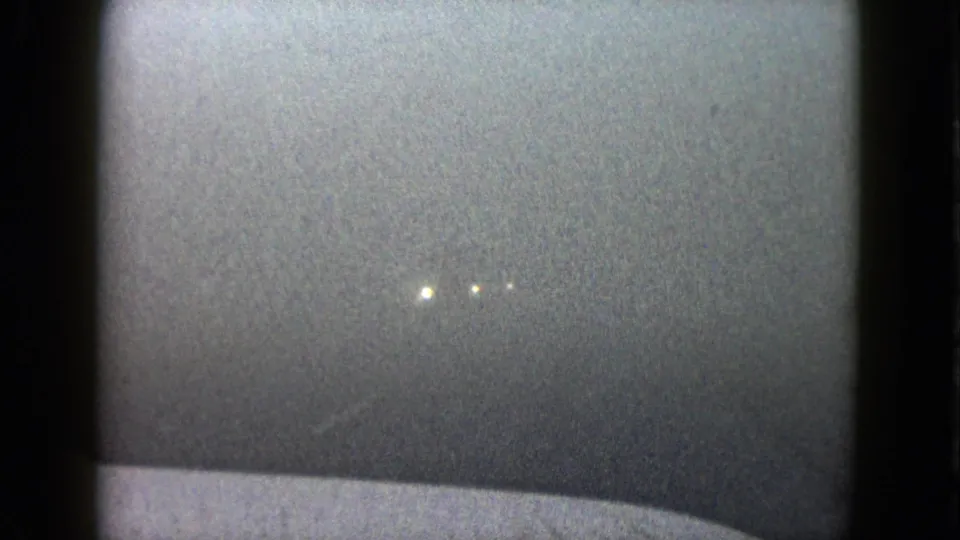 1958 Las Vegas frame with faint headlights emerging through haze above a pale vehicle hood or dashboard edge.