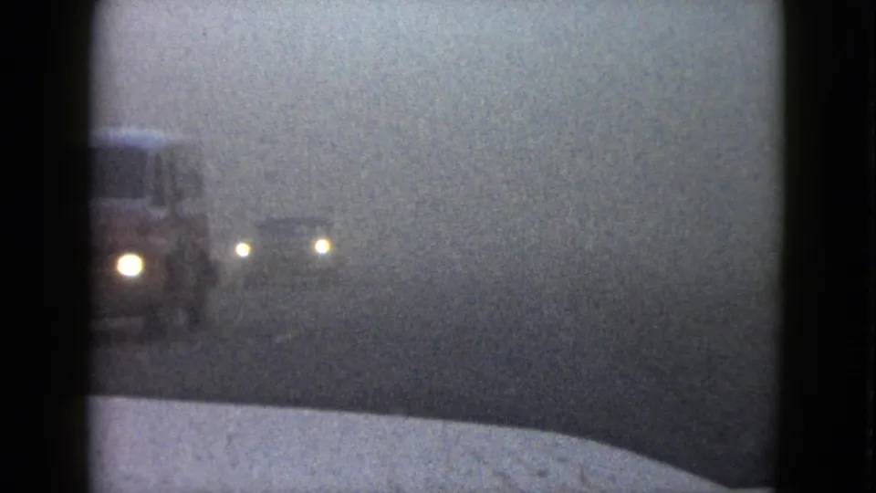 1958 Las Vegas home-movie frame with car headlights diffused by haze near the left side of the driving view.