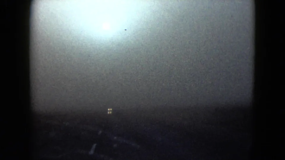 1958 Las Vegas-area 8mm frame with heavy exposure flare over a road view, leaving faint roadway details and small distant lights visible.
