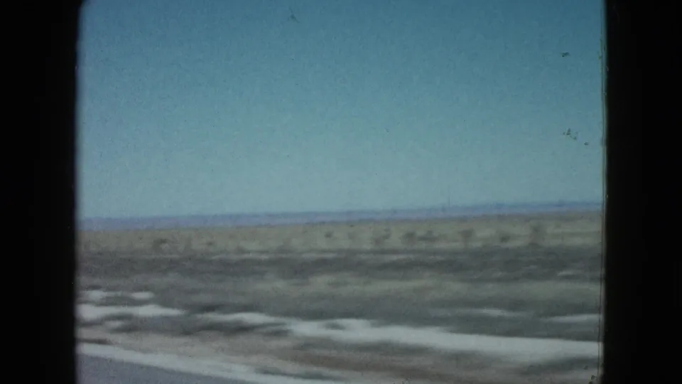 Final 1958 8mm car-window view of desert flats, roadside blur, and a low horizon near Las Vegas.